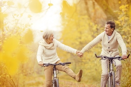 34112000 - active seniors riding bike in autumn nature. they relax outdoor.