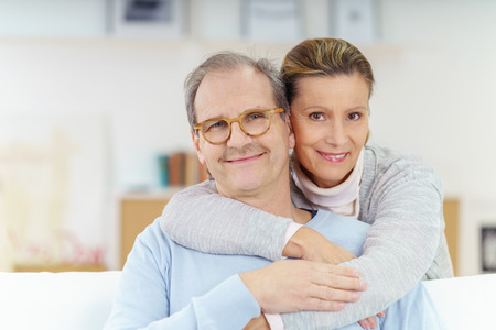 51788398 - smiling couple in their fifties relaxing and embracing at home